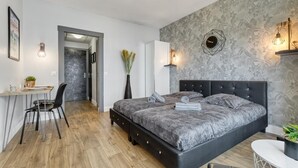 A modern bedroom with a large bed, a desk, and a chair. There is a door leading to another room. - Victoria CHIC Studio - Downtown - Balcony with Mountain Views (Aix les Bains)