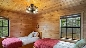 A cabin with two wooden beds, a hanging light fixture, and windows with a view of the outdoors. - Southwind Ridge - Mountain View | Screened porch | Fireplace (Morganton)