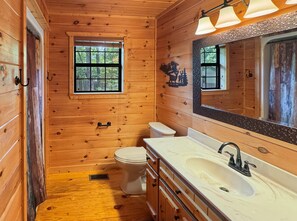 A wooden cabin bathroom with a toilet, sink, and window. - Southwind Ridge - Mountain View | Screened porch | Fireplace (Morganton)