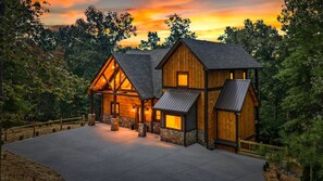 A two-story log cabin with a stone foundation, large windows, and a metal roof. - Hope Ridge Manor - Pet Friendly | Firepit | Hot Tub | Game Room (Blue Ridge)