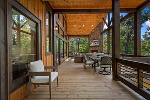 A wooden deck with outdoor furniture, a television, and a stone wall. - Hope Ridge Manor - Pet Friendly | Firepit | Hot Tub | Game Room (Blue Ridge)