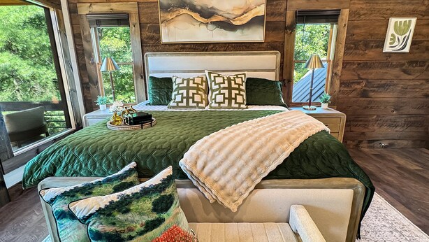 A bedroom with a large bed, a headboard, and a view of greenery through the windows. - Hope Ridge Manor - Pet Friendly | Firepit | Hot Tub | Game Room (Blue Ridge)