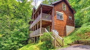 Una baita di legno con un balcone e una scala che conduce all'ingresso.