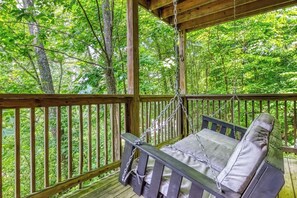 A wooden deck with a swing chair and a view of a forest. - Gatlinburg: 4 King Ensuites, Hot Tub, Pool Table (Gatlinburg)