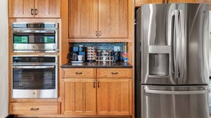 Una cocina con gabinetes de madera, electrodomésticos de acero inoxidable, incluyendo un refrigerador y una cafetera.