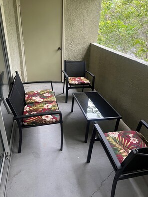 Un balcon avec deux chaises et une table, agrémenté de coussins à motifs floraux.