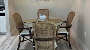 A dining area with a round table, wicker chairs, a hanging light fixture, and two framed pictures on the wall. - Cozy Avalon 1-bedroom in beautiful Clearwater-newly remodeled (Clearwater)