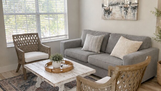A living room with a grey sofa, two wicker chairs, a coffee table, and a large window with blinds. - Cozy Avalon 1-bedroom in beautiful Clearwater-newly remodeled (Clearwater)