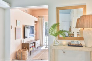 A well-lit living room with a television, a large mirror, a lamp, and a bookshelf. - Designer Sarasota Retreat - Heated Pool - Minutes to Siesta Key (Sarasota)