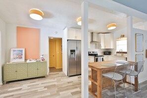 Eine moderne Küche mit Esstisch aus Holz, Edelstahlgeräten und einem grünen Schrank.