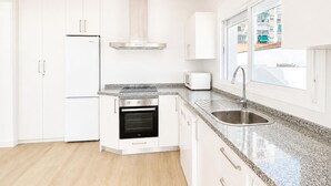 A modern kitchen with white cabinetry, a stainless steel range, a built-in oven, a microwave, and a window with a view of buildings. - Awesome home in Nerja with private swimming pool, can be inside or outside (Nerja)