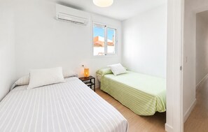 Ein Schlafzimmer mit zwei Betten, einem Fenster und einer Klimaanlage.