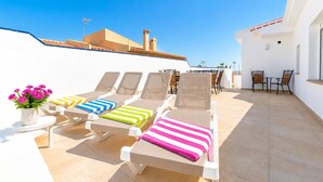 A rooftop terrace with sun loungers, a table with chairs, and a potted plant. - Awesome home in Nerja with private swimming pool, can be inside or outside (Nerja)