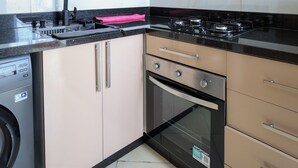 Et moderne køkken med beige skabe, en indbygget ovn, en mikrobølgeovn og en gasblus.