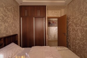 Ein Schlafzimmer mit einem Bett, einem Kleiderschrank und einer Tür zu einem anderen Raum.