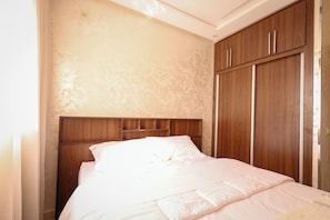 Ein Schlafzimmer mit Holz-Kopfteil, einem Bett mit weißer Bettwäsche und einem Schrank mit Holztüren.
