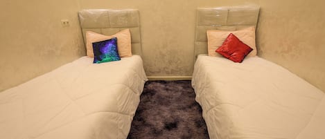 A room with two single beds, each with a headboard and a pillow.