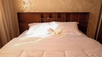Ein ordentlich bezogenes Bett mit einem hölzernen Kopfteil, einer weißen Daunendecke und Kissen.