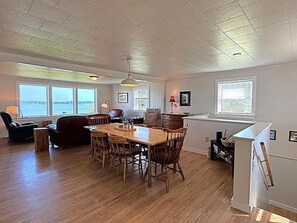 A spacious living area with a wooden dining table and chairs, a sofa, and a kitchen area with a refrigerator and sink. - The Blue Pearl. Charming 3-bedroom house in adorable Lubec! (Lubec)