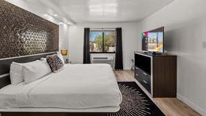 Habitación de hotel moderna con una cama grande, televisor de pantalla plana, un panel decorativo en la pared y vistas al exterior.