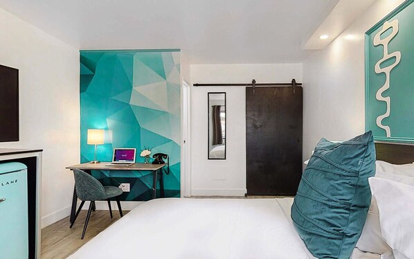 A hotel room with a bed, a desk with a computer, a chair, and a minibar. - Cozy 1-bedroom hotel in charming Albuquerque with AC (Albuquerque)