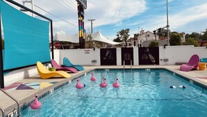 Una piscina con flamencos inflables y sillas de descanso coloridas.