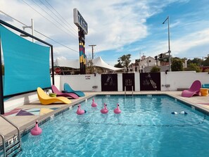 A swimming pool with inflatable flamingos and colorful lounge chairs. - Cozy 1-bedroom hotel in charming Albuquerque with AC (Albuquerque)