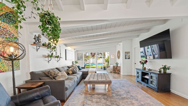 A spacious living room with a sectional sofa, a coffee table, and a television mounted on the wall. - Spacious 4-bedroom house in charming Toluca Woods (Los Angeles)
