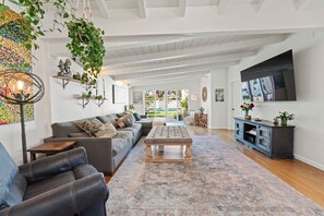 Ein geräumiges Wohnzimmer mit einer Eckcouch, einem Couchtisch und einem an der Wand befestigten Fernseher.