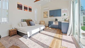 A bedroom with a large bed, a small desk, and a kitchenette with blue cabinets. - Spacious 4-bedroom house in charming Toluca Woods (Los Angeles)