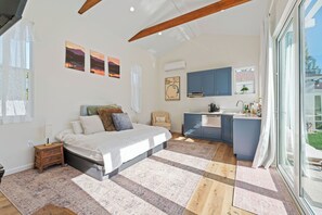Ein Schlafzimmer mit einem großen Bett, einem kleinen Schreibtisch und einer Küchenzeile mit blauen Schränken.