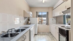 Eine kleine Küche mit Spüle, Herd und Kühlschrank.