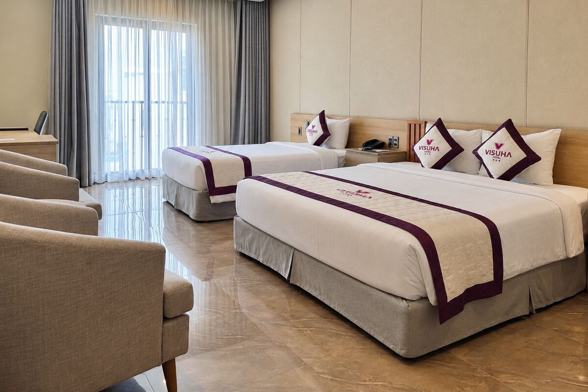 A hotel room with two beds, a desk, and a chair.