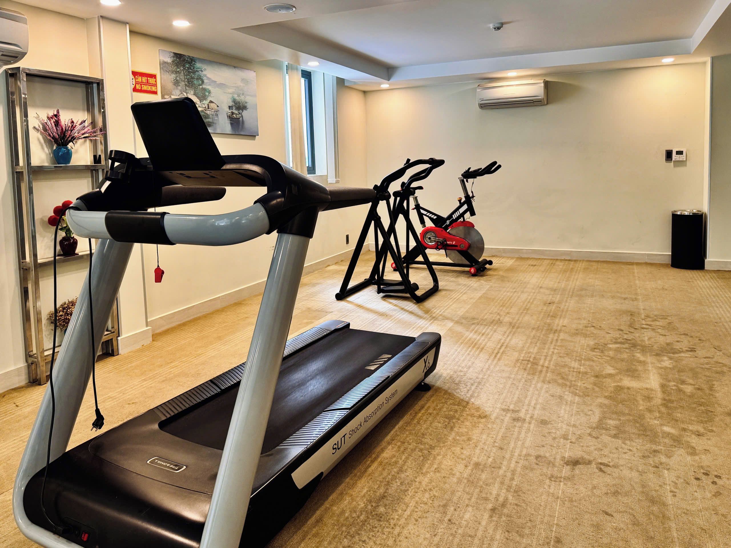 Un gimnasio en casa con cinta de correr, bicicletas estáticas y equipo de ejercicio.