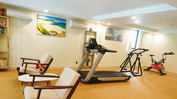 Un gimnasio en casa con equipo de ejercicio, incluyendo una caminadora, bicicleta estática y una silla.