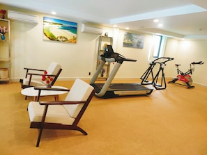 A home gym with exercise equipment including a treadmill, stationary bike, and chair.