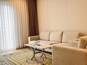 A modern living room with a beige sofa, a small table, and a patterned rug.