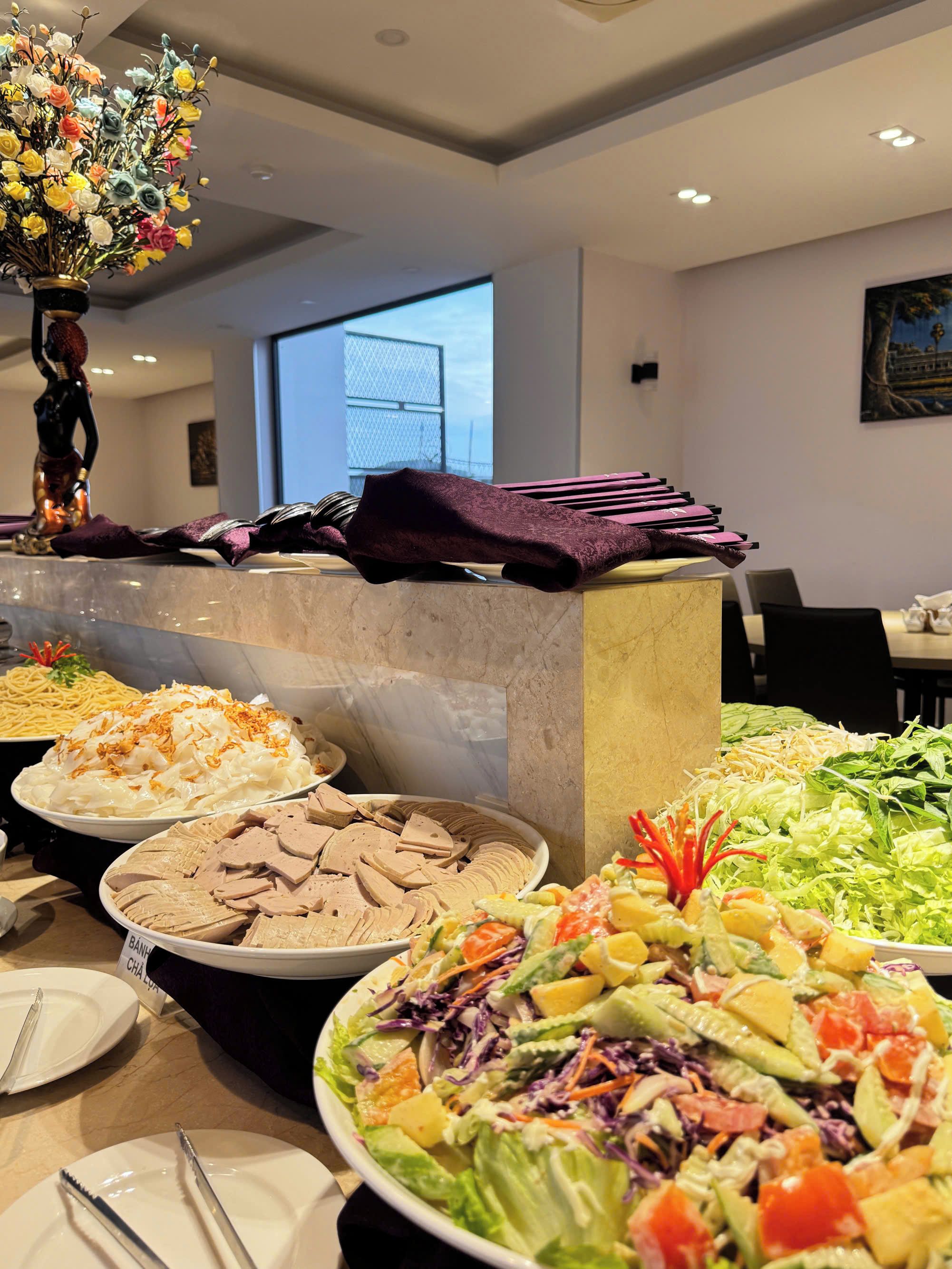 A buffet with various dishes, a decorative vase, and a window view.