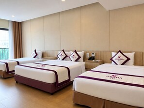 A hotel room with three beds, each with a matching headboard and pillow, and a bedside table with a phone and a lamp. - VISUHA HOTEL   (Ha Tien)