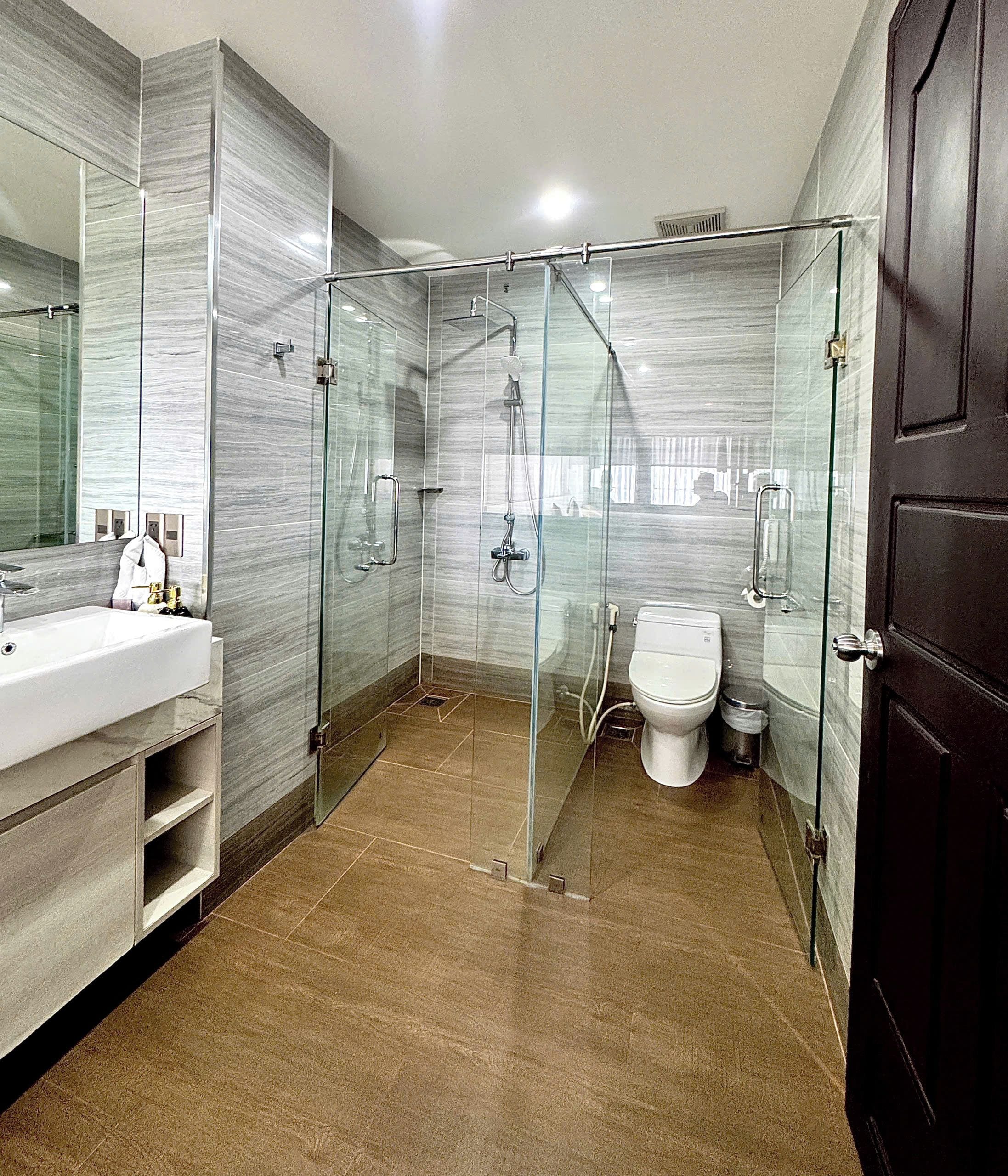Un baño moderno con ducha envuelta en vidrio, un lavabo blanco y un inodoro.