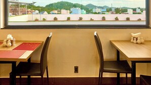Comedor con vista panorámica a través de un ventanal de una ciudad, incluyendo edificios y zonas verdes.