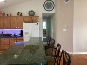 A kitchen with a central island, wooden cabinets, a white refrigerator, and a wall-mounted clock. - Spacious 3br/2bth Wildwood Condo — Walk to the Beach, Boardwalk & Downtown! (Wildwood)