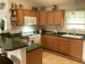 A kitchen with wooden cabinets, a stove, a microwave, and a sink. - Spacious 3br/2bth Wildwood Condo — Walk to the Beach, Boardwalk & Downtown! (Wildwood)