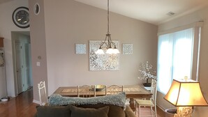 Ein Wohnzimmer mit einer Couch, einem Esstisch mit Stühlen, einer Chandelier und einer Lampe.