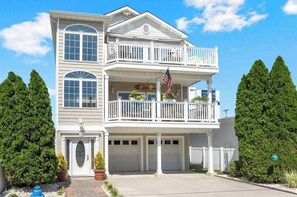 Une maison à deux étages avec un balcon, un garage et une porte d’entrée.