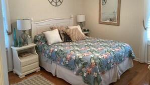 Ein Schlafzimmer mit einem Bett, Nachttischen, einer Lampe, einer Kompass-Wanddekoration und einem gerahmten Bild.