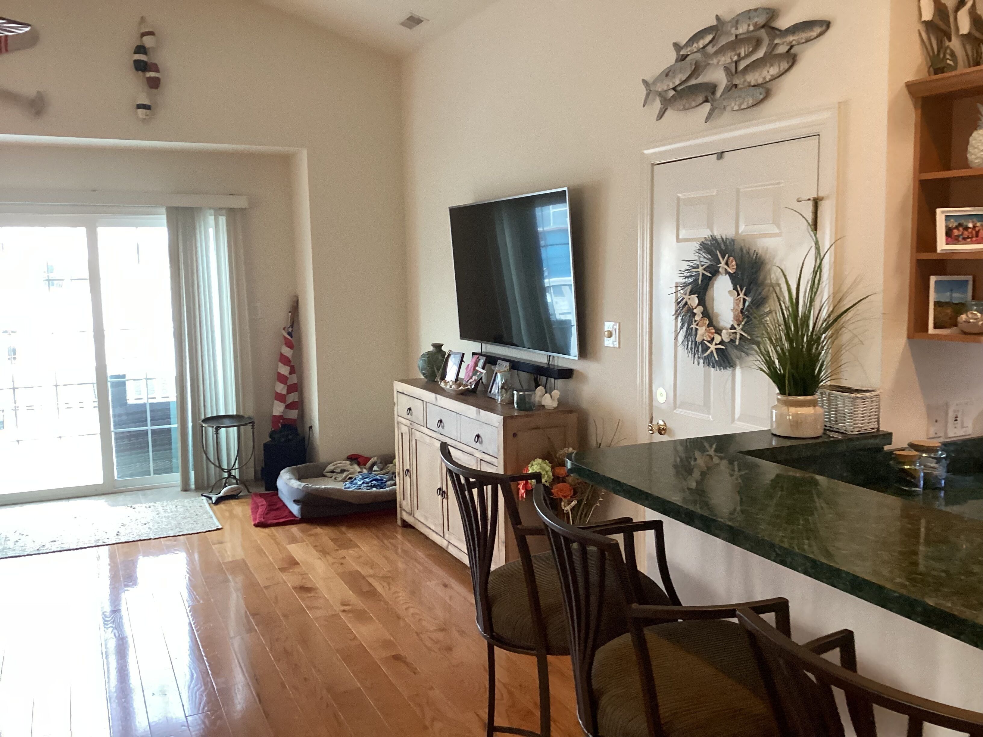 A modern kitchen with a large island, wooden cabinets, and a flat-screen TV mounted above the island.