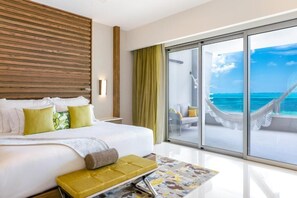 Ein Hotelzimmer mit einem großen Bett, Meerblick und einer Hängematte vor dem Fenster.