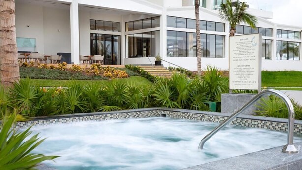 A modern hotel with a spa area, including a hot tub surrounded by lush greenery and a well-maintained garden. - Garza Blanca Resort and Spa (Punta Sam)