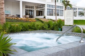 A modern hotel with a spa area, including a hot tub surrounded by lush greenery and a well-maintained garden.